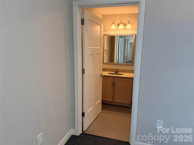 a view of a hallway with wooden floor and a kitchen