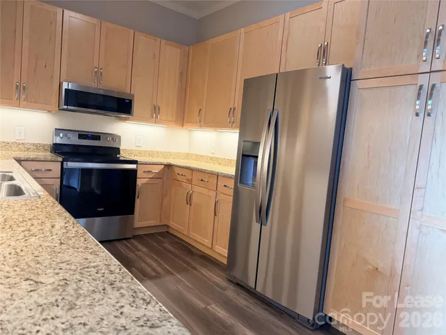 a kitchen with stainless steel appliances granite countertop a refrigerator and a stove top oven