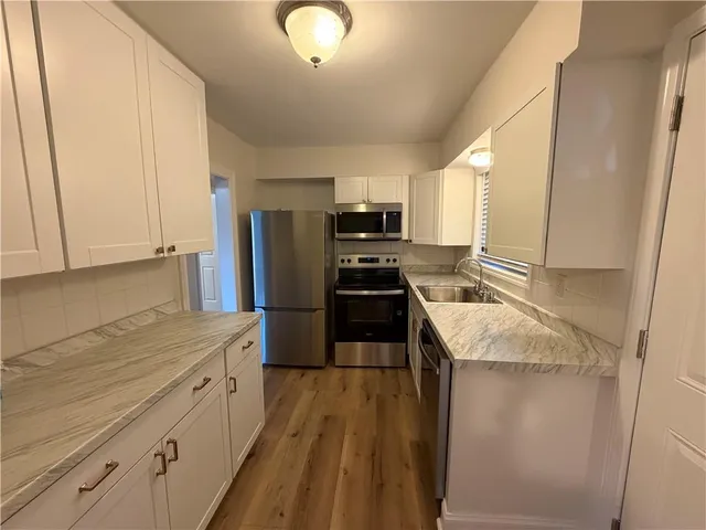 a kitchen with granite countertop a sink stove and refrigerator
