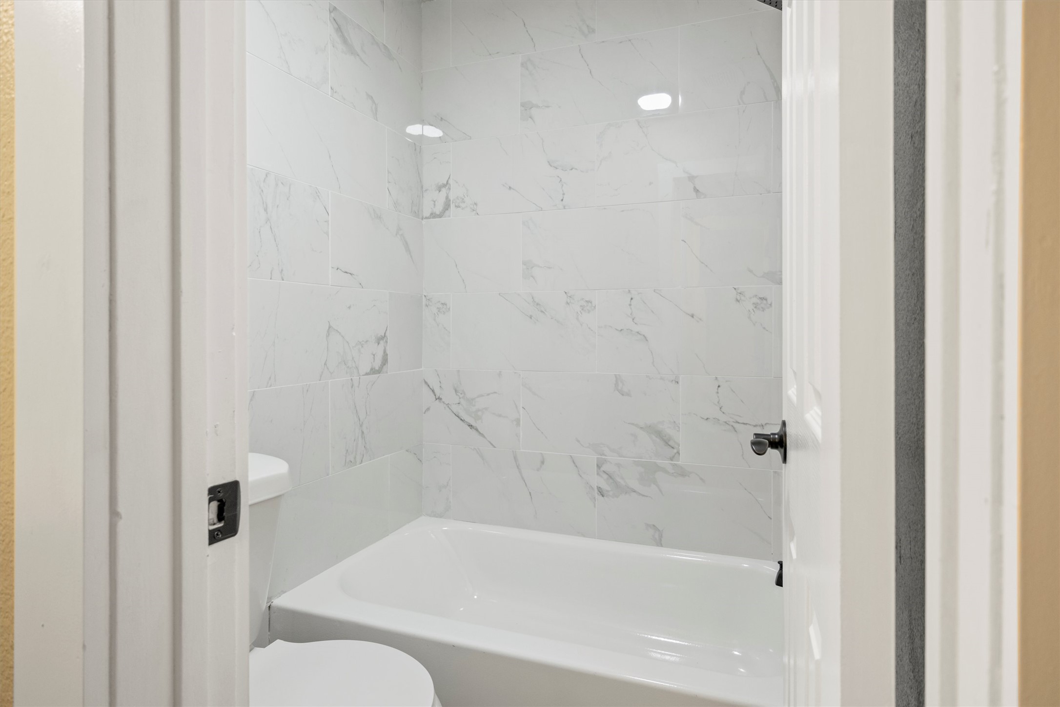 502 Pin Tail Lane Taylor, TX 76574 - Photo 5 of 26 White tiled shower and tub combination featuring a white porcelain tub and marble-patterned wall tiles