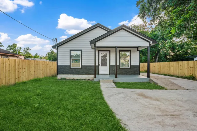 a view of a house with a yard and wooden fence