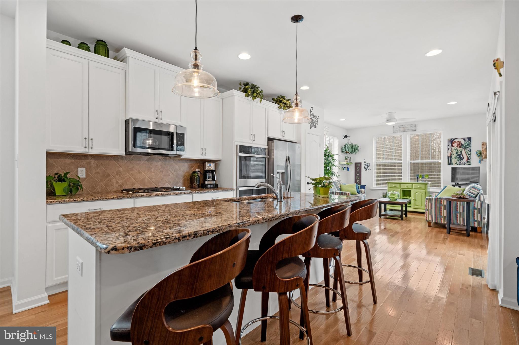 5338 Newman Lane Middletown, DE 19709 - Photo 24 of 61 a kitchen with stainless steel appliances granite countertop a stove a sink a microwave a dining table and chairs