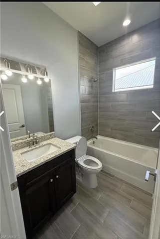 a bathroom with a granite countertop sink toilet mirror and bathtub