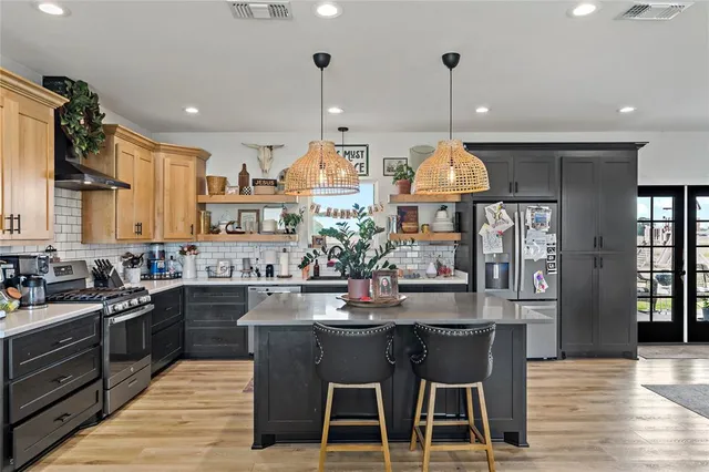 a kitchen with stainless steel appliances granite countertop a sink a stove and a wooden floors