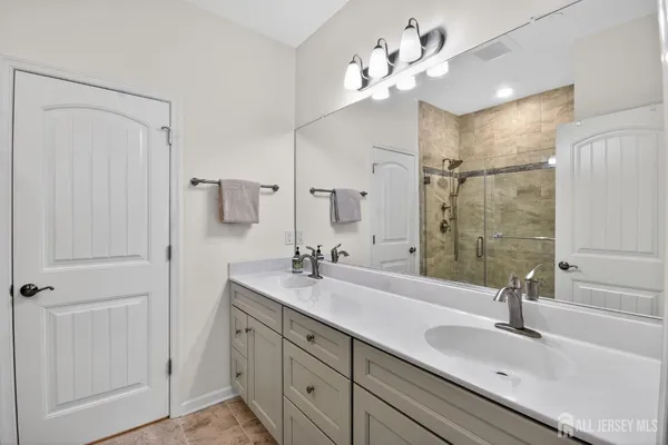 a bathroom with a double vanity sink mirror and shower