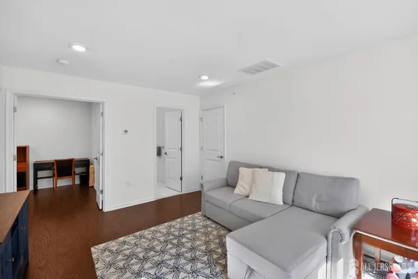 a living room with furniture and a dining table with wooden floor