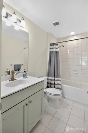 a bathroom with a granite countertop sink a toilet a mirror a vanity and bathtub