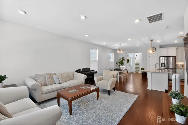 a living room with furniture wooden floor and a kitchen