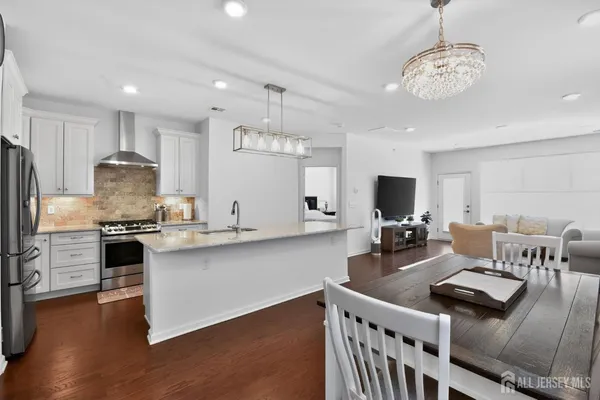 a open kitchen with stainless steel appliances granite countertop a stove refrigerator a dining table and chairs with wooden floor