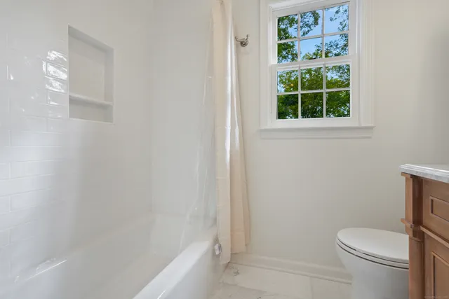 a white toilet sitting next to a bath tub