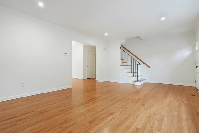 a view of an empty room with wooden floor and stairs