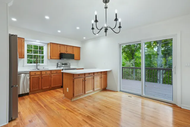 a open kitchen with stainless steel appliances granite countertop a stove a sink dishwasher a microwave oven with cabinets and wooden floor