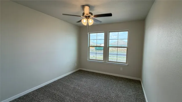 an empty room with a window and a fan