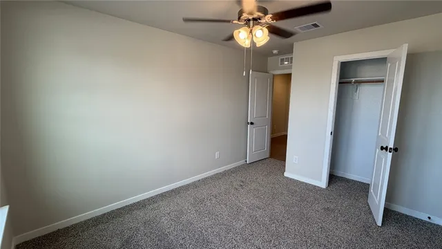 an empty room with a chandelier fan and a bathroom