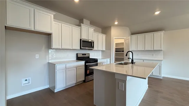 a kitchen with stainless steel appliances a sink a stove a microwave a sink a refrigerator and cabinets