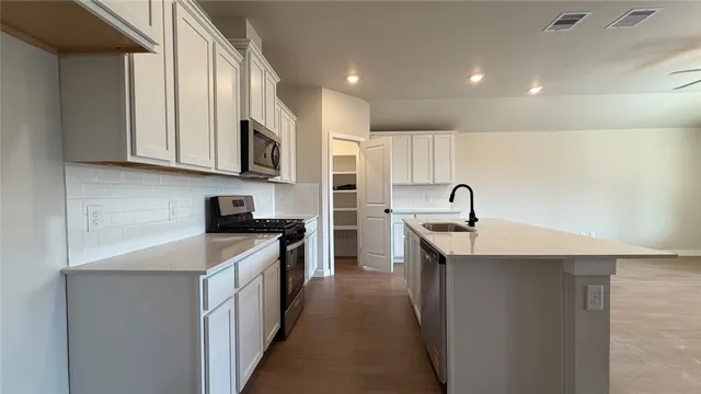 a kitchen with stainless steel appliances granite countertop a sink stove top oven and refrigerator