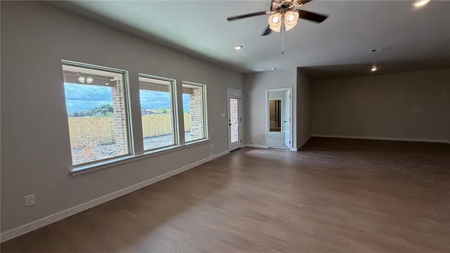 an empty room with chandelier fan and windows
