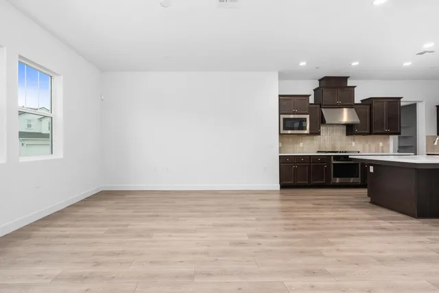 a large kitchen with stainless steel appliances a large counter top a stove and a refrigerator