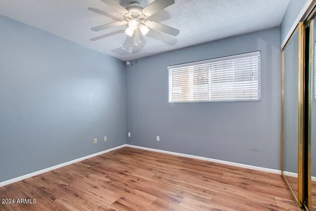 a view of empty room with wooden floor and fan