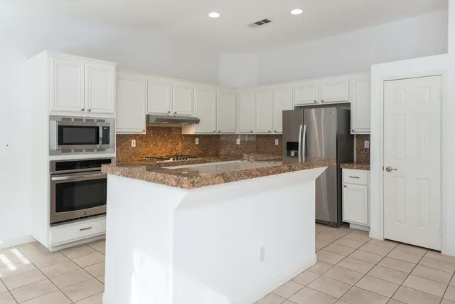a kitchen with stainless steel appliances granite countertop a refrigerator stove and microwave