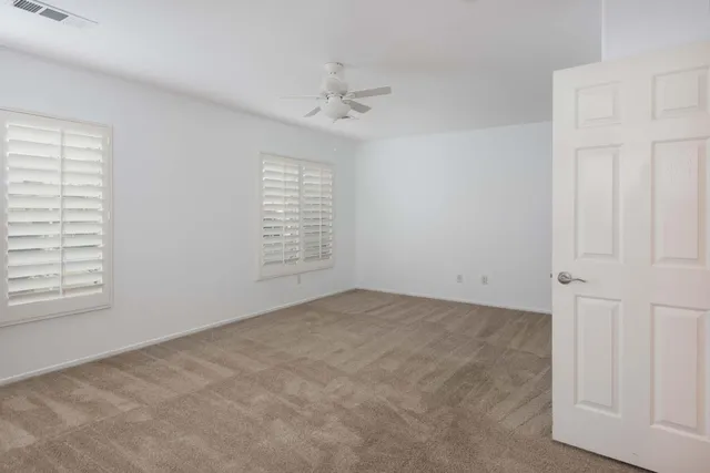 an empty room with windows and fan