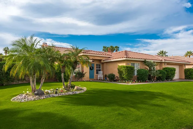 a view of a house with a big yard and palm trees
