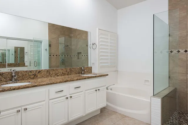 a bathroom with a granite countertop sink mirror and a bathtub