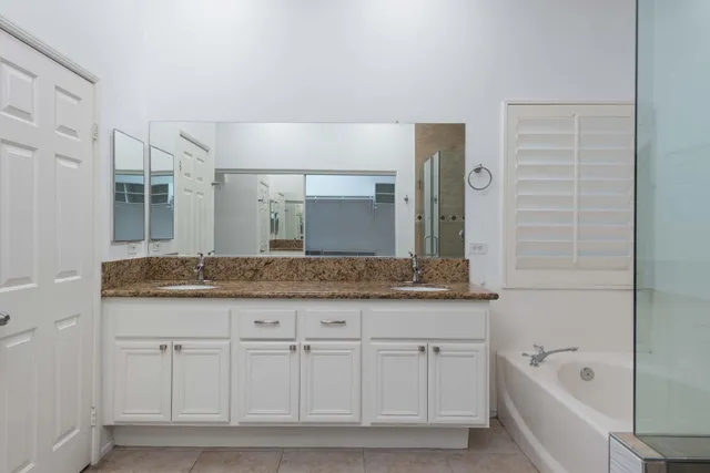 a bathroom with a granite countertop sink a large mirror and a bathtub