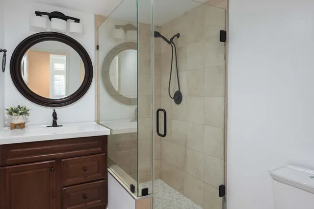 a bathroom with a granite countertop sink a mirror and shower