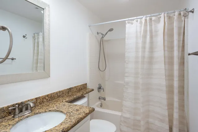a bathroom with a granite countertop sink toilet and shower