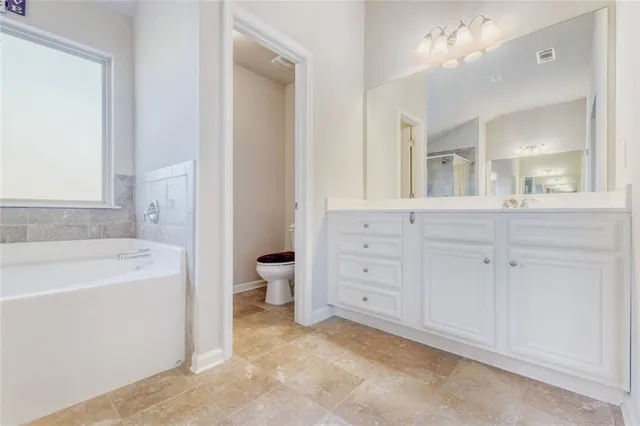 a spacious bathroom with a tub sink and mirror