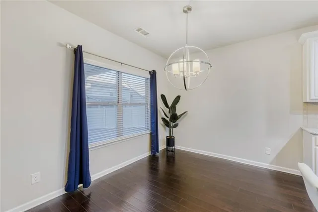 an empty room with wooden floor mirror and windows