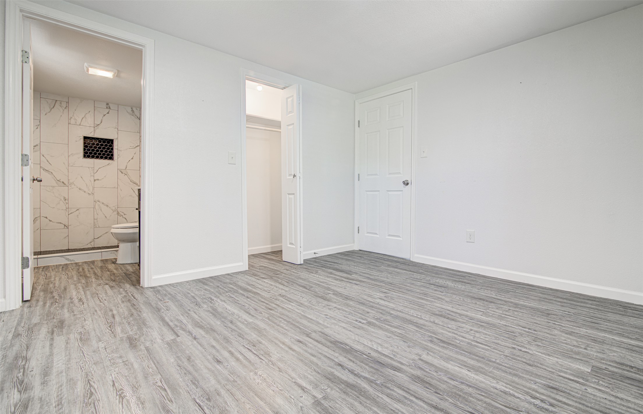 1807 San Jose Street Georgetown, TX 78626 - Photo 13 of 21 The room features light-toned plank flooring, a doorway leading to a tiled bathroom, and a closet opening.