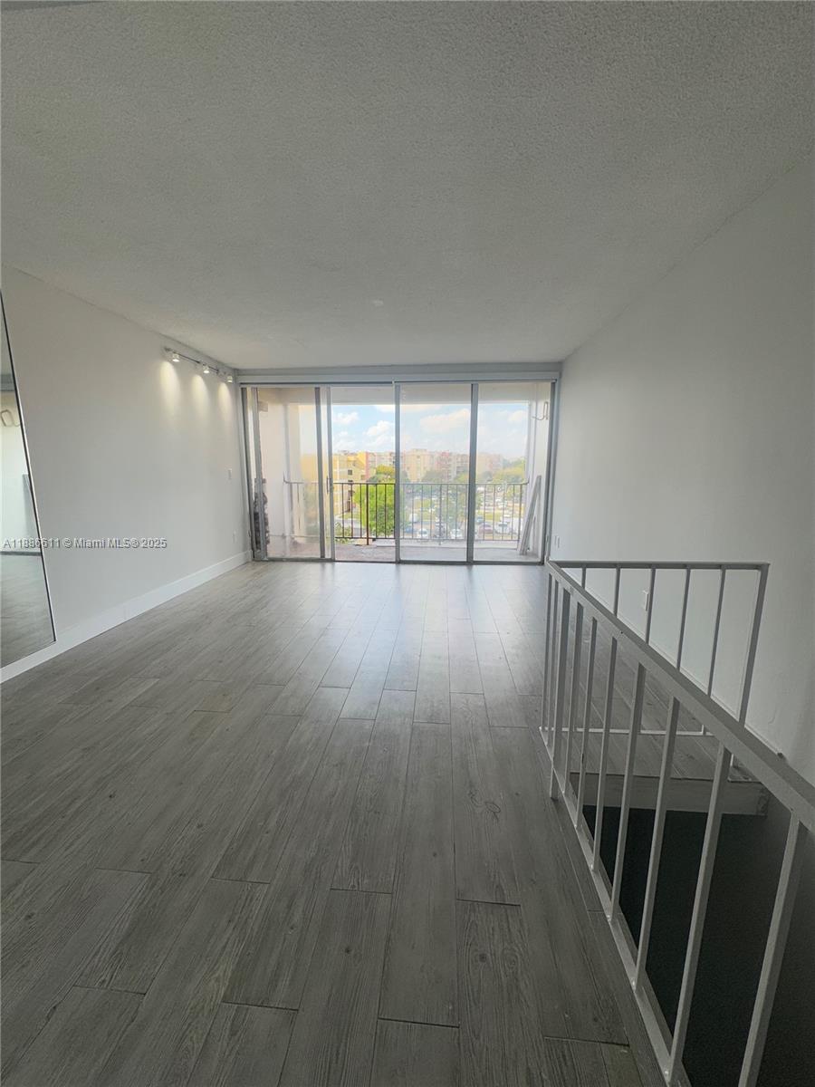 9220 Fontainebleau Boulevard, Unit 507 Miami, FL 33172 - Photo 1 of 9 an empty room with wooden floor and windows