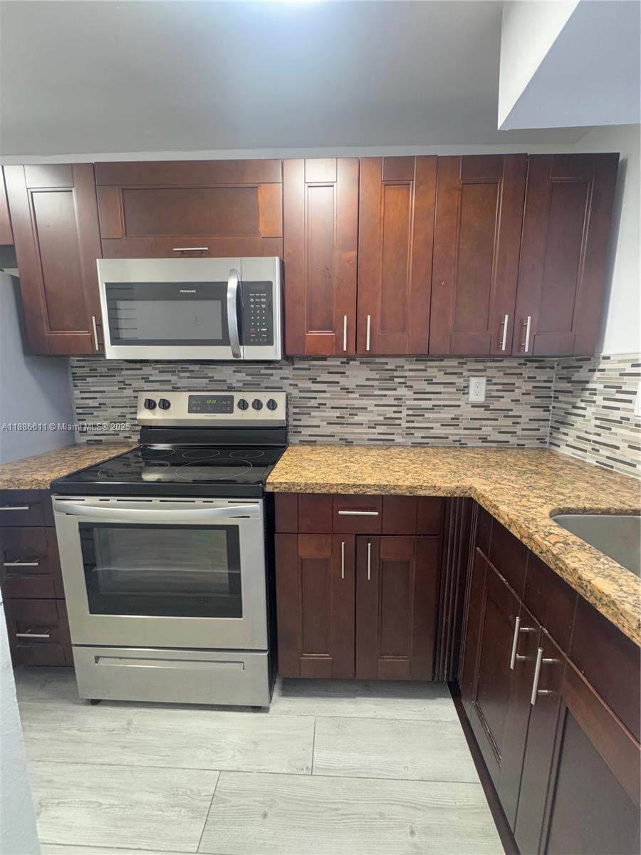 9220 Fontainebleau Boulevard, Unit 507 Miami, FL 33172 - Photo 2 of 9 a kitchen with a stove microwave and sink
