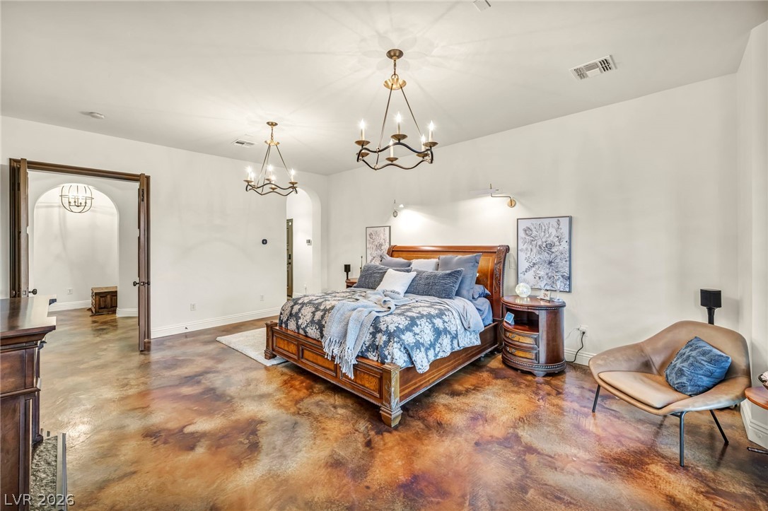 1158 Christian Road Henderson, NV 89002 - Photo 25 of 71 This primary bedroom features elegant light fixtures and rich flooring, offering a spacious and inviting retreat.