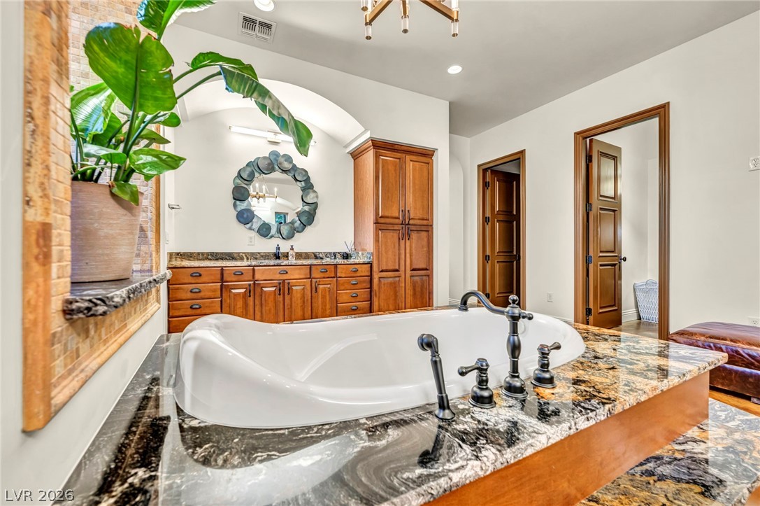 1158 Christian Road Henderson, NV 89002 - Photo 28 of 71 This primary bathroom offers a relaxing retreat with a deep soaking tub and elegant granite countertops.