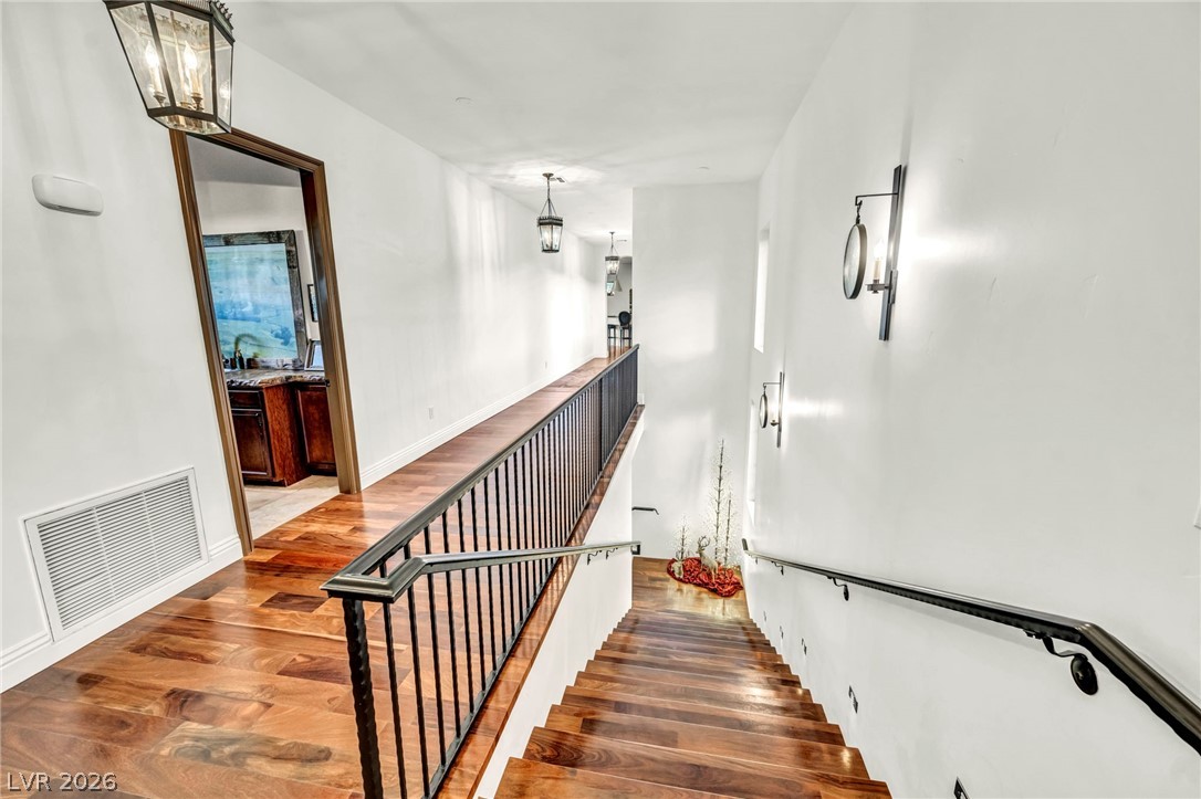 1158 Christian Road Henderson, NV 89002 - Photo 34 of 71 This spacious hallway features rich hardwood flooring and elegant wall sconces, creating a refined atmosphere.