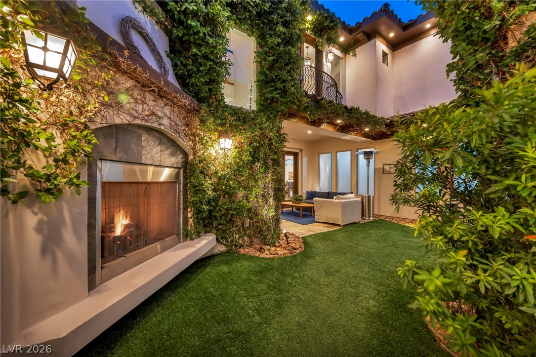1158 Christian Road Henderson, NV 89002 - Photo 5 of 71 This private courtyard offers a cozy outdoor living space with lush greenery and a warm fireplace.