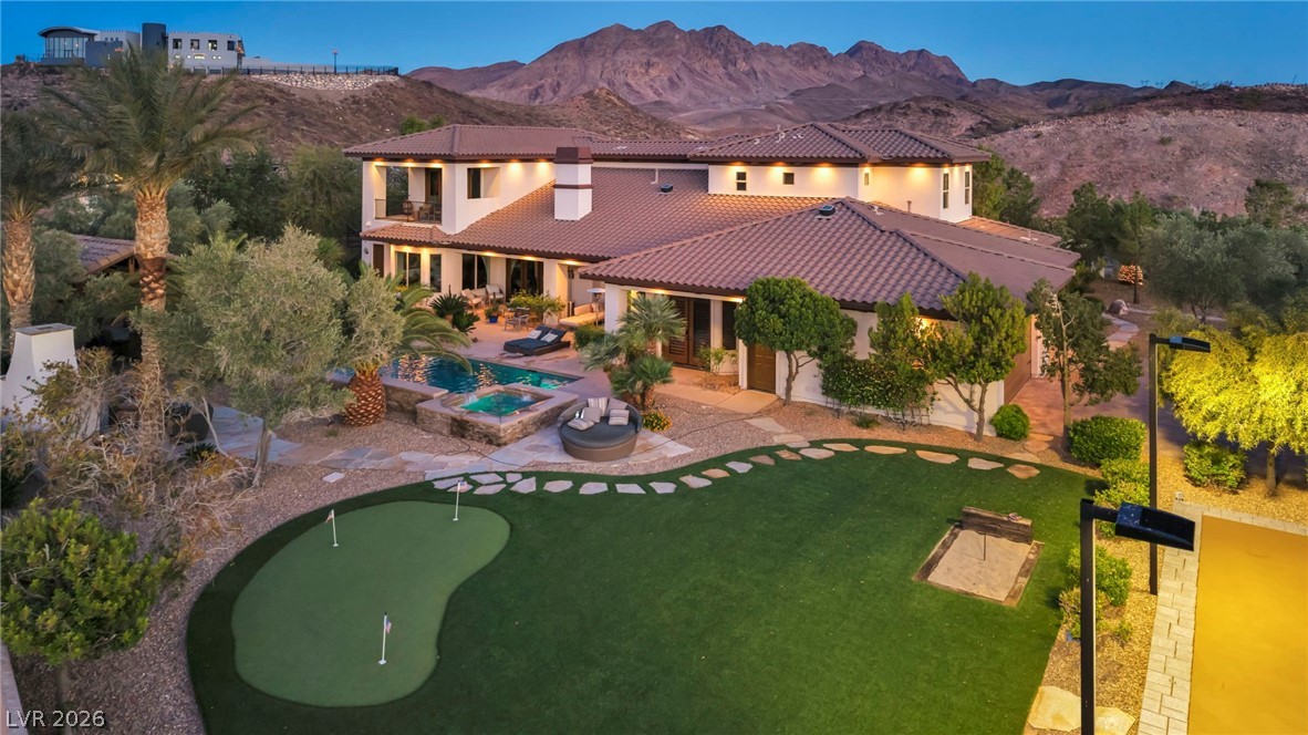 1158 Christian Road Henderson, NV 89002 - Photo 67 of 71 This spacious estate showcases a putting green and inviting pool against a mountainous backdrop.