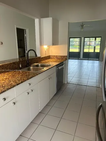 a large kitchen with granite countertop a toilet a sink and a large window