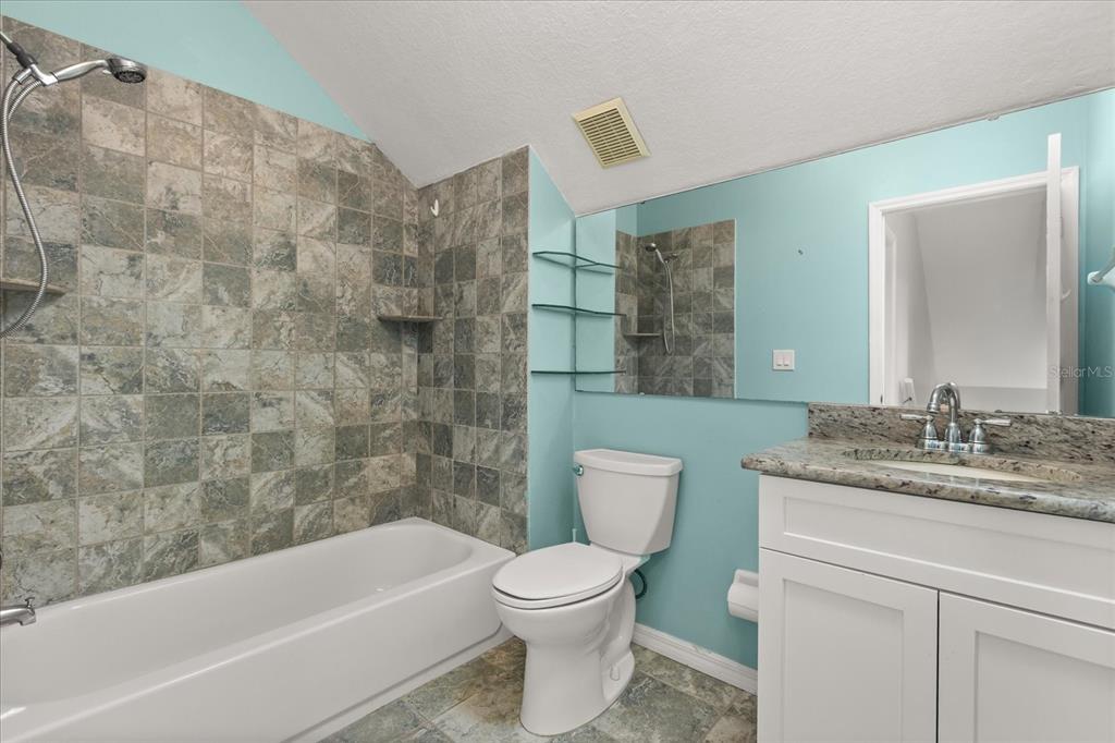 13607 Springtide Court Orlando, FL 32826 - Photo 14 of 32 a bathroom with a granite countertop bathtub shower sink mirror vanity and toilet