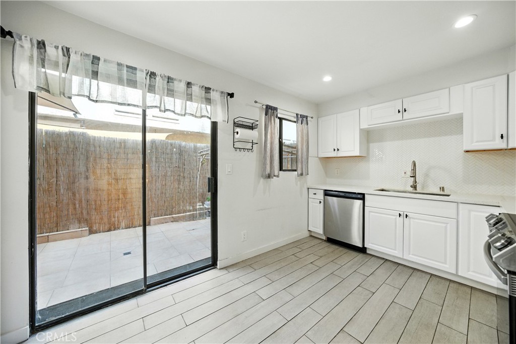 14937 Sherman Way, Unit 7 Van Nuys, CA 91405 - Photo 13 of 37 a kitchen with granite countertop a refrigerator a sink and white cabinets