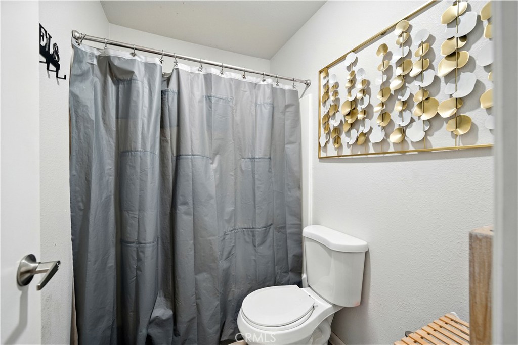 14937 Sherman Way, Unit 7 Van Nuys, CA 91405 - Photo 28 of 37 a white toilet sitting next to a shower curtain