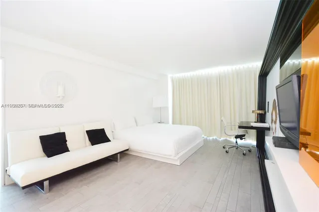 a bedroom with a bed and a flat tv screen on the dresser