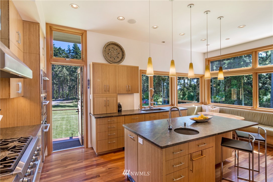 1224 Shark Reef Road Lopez Island, WA 98261 - Photo 10 of 34 a kitchen with a stove a sink and a dining table with wooden floor