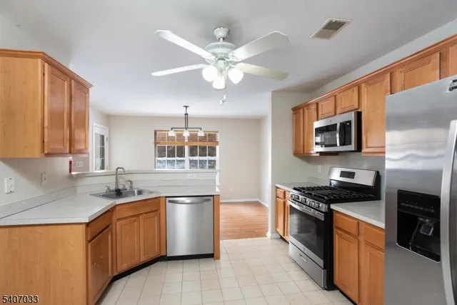a kitchen with granite countertop stainless steel appliances a sink cabinets and wooden floor