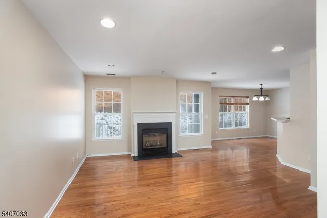 an empty room with wooden floor fireplace and windows