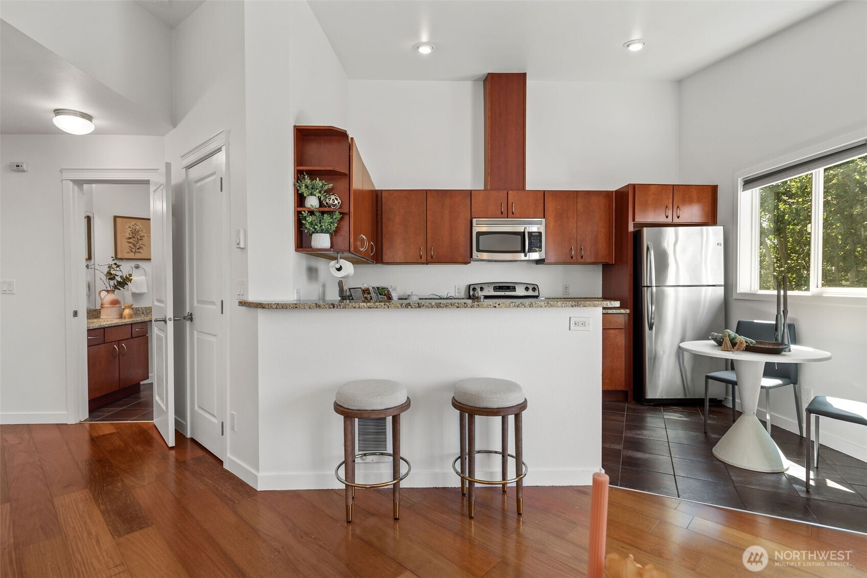 1125 North 93rd Street, Unit 6 Seattle, WA 98103 - Photo 14 of 35 a kitchen with stainless steel appliances granite countertop a stove top oven a refrigerator a dining table and chairs with wooden floor