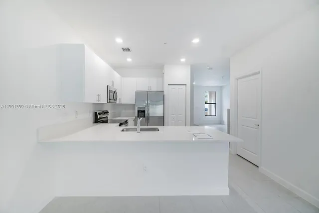 a large white kitchen with kitchen island white cabinets and stainless steel appliances